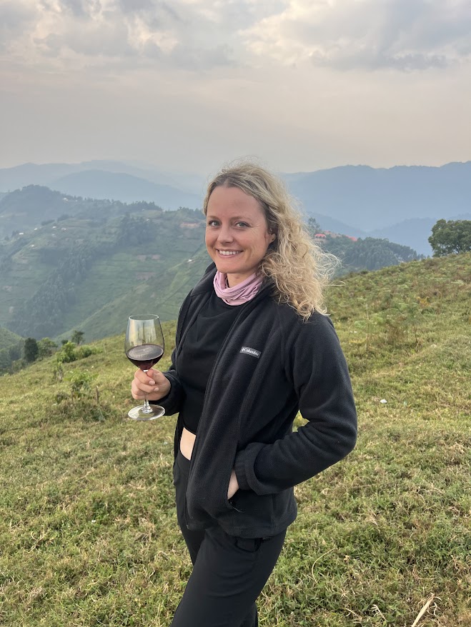 Woman holding glass of wine with view of rolling mountains in background.